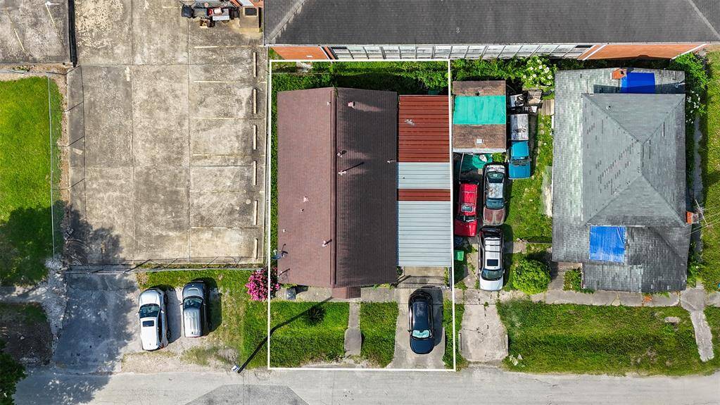 This aerial photo shows a property with a brown-roofed house. The setting is urban with a mix of residential and commercial surroundings.