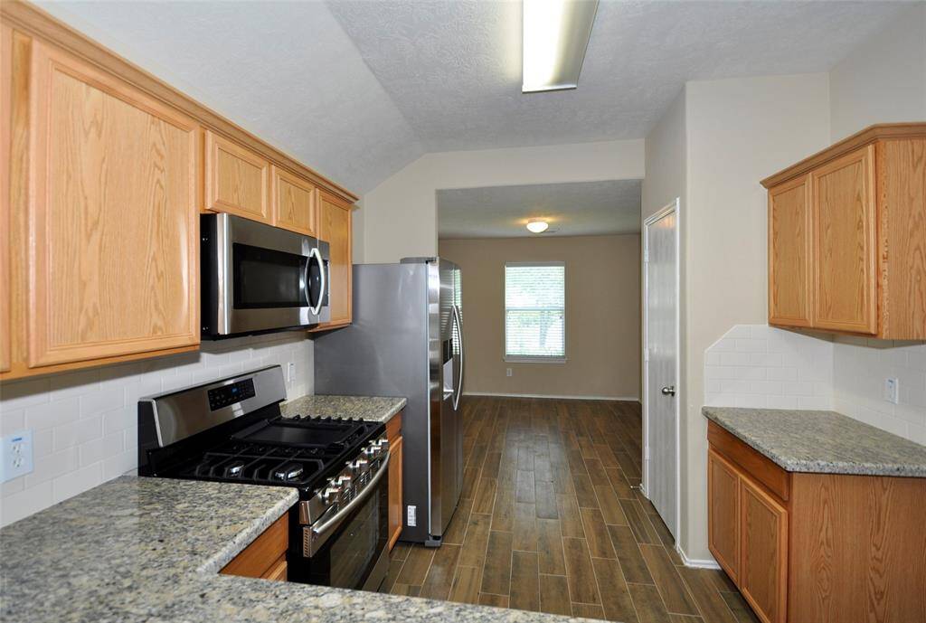 The kitchen has a pantry closet and continued wood-look tile flooring.