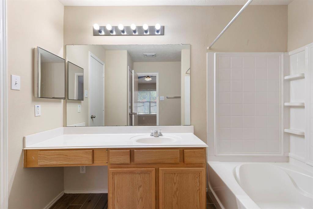 The primary bath features cultured marble counters, tile floors, vanity space and tub/shower combination.