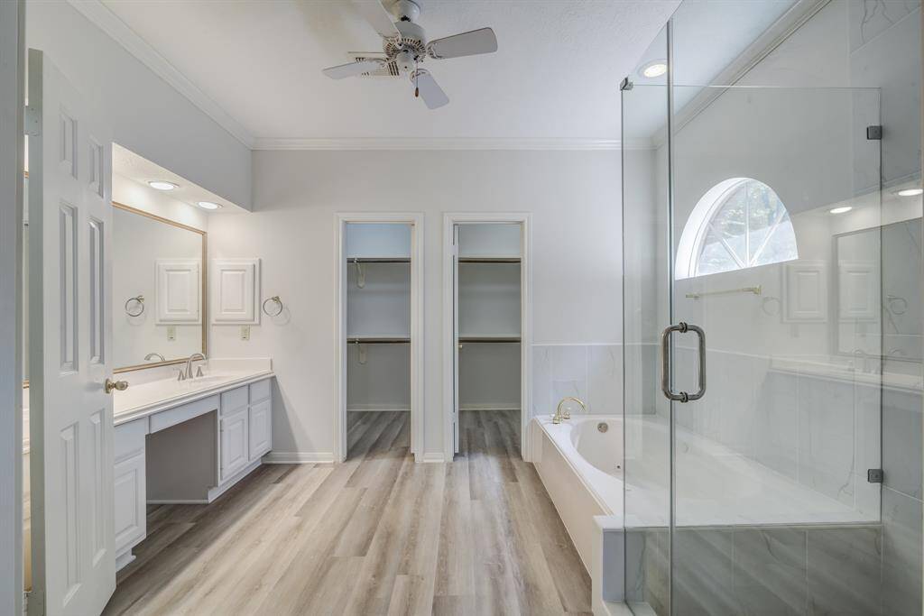 Gorgeous updated shower, dual sink vanity and two walk in closets along with soaking tub, in this large en suite primary bathroom.