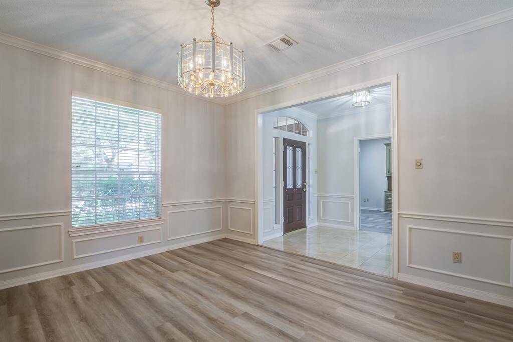 Formal dining space freshly painted and updated plank flooring. Crown molding and very on trend wall paneling give this home an elevated style.