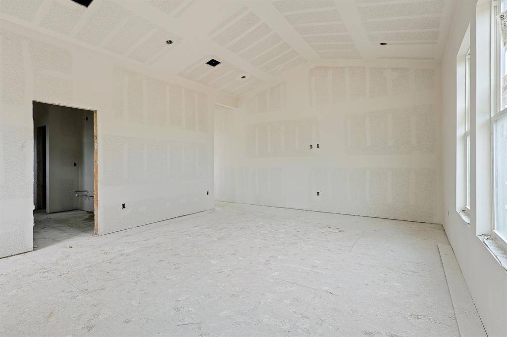 This perspective highlights the generous space and bright ambiance of the primary suite. With ample room for a sitting area or workspace, the vaulted ceilings and large windows enhance the airy, tranquil atmosphere—making it a true sanctuary in the home.