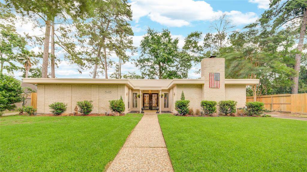 Charming one-story brick home with a welcoming front walkway and manicured lawn nestled beneath mature trees.