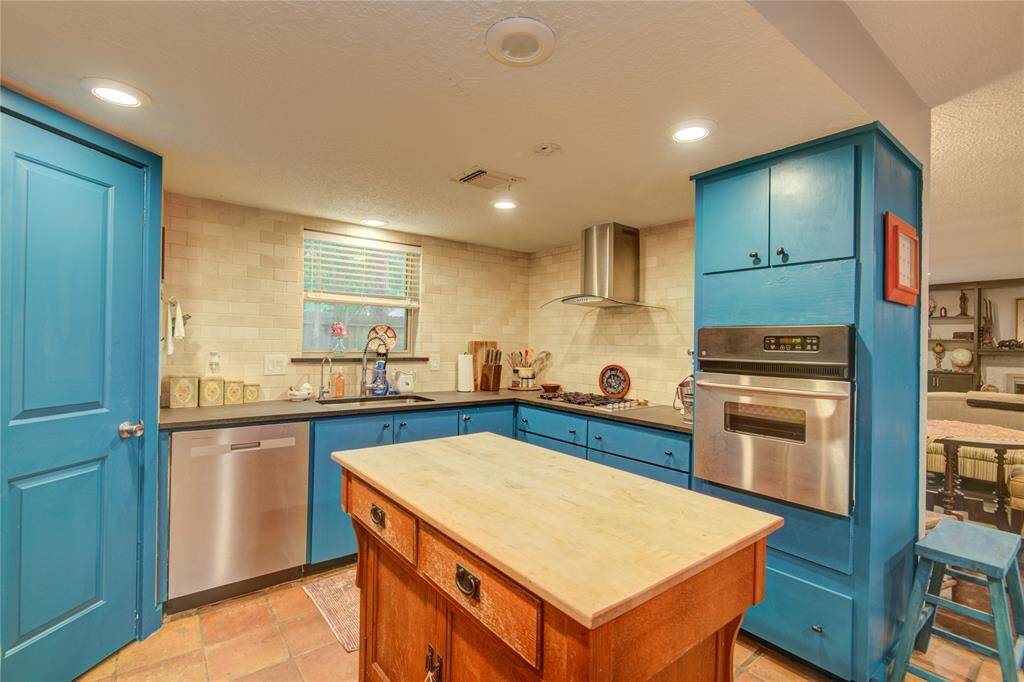 The kitchen features sleek stainless steel appliances and a striking glass vent hood over the gas cooktop, blending style with functionality.