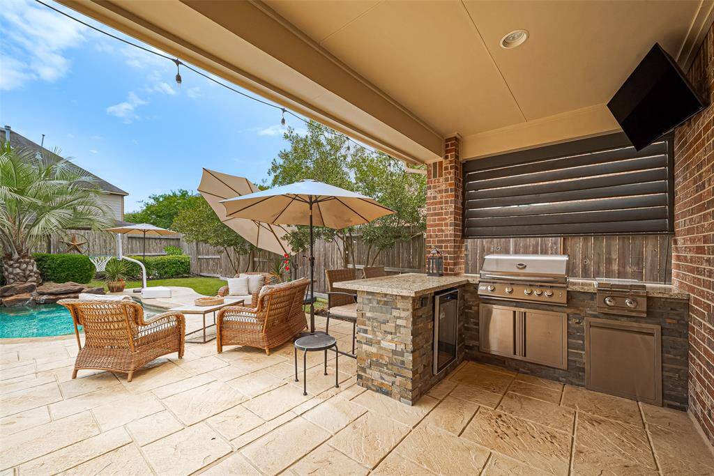 Outdoor summer kitchen with beverage refrigerator, grill, 2 gas burners and storage conveniently located under a covered patio