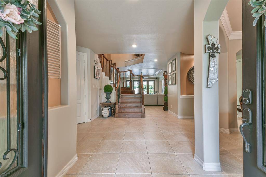Beautiful solid wood double door entry with iron detailing. Graceful archways with neutral paint. Cohesive 16" large tiling in the main living area, dining room, and kitchen. When you enter the home you see a beautiful wood staircase with iron balusters, formal dining room to the right framed with archways, and a home office to the left with french doors and solid wood flooring.