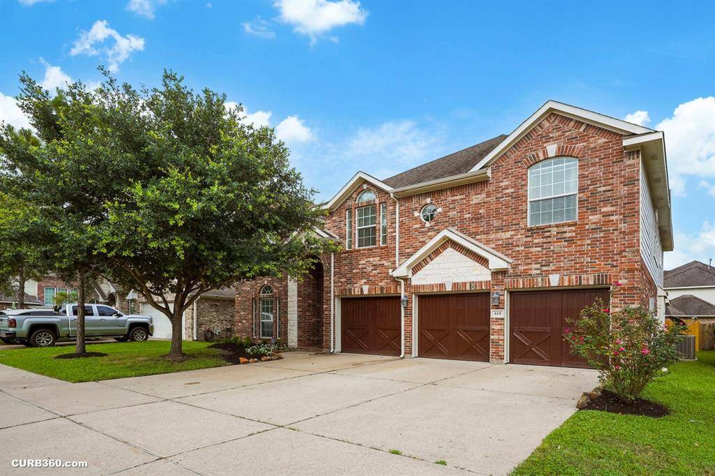 This is a spacious two-story brick home featuring large windows and a three-car garage.