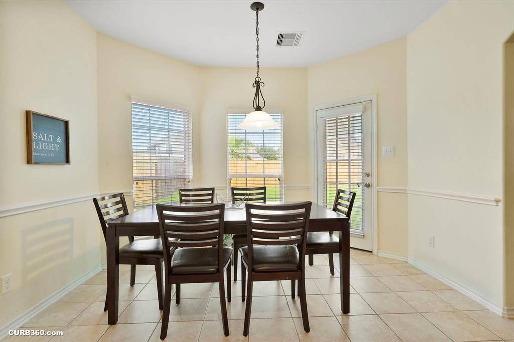 Bright dining area with large windows, tile flooring, and a door leading to the backyard