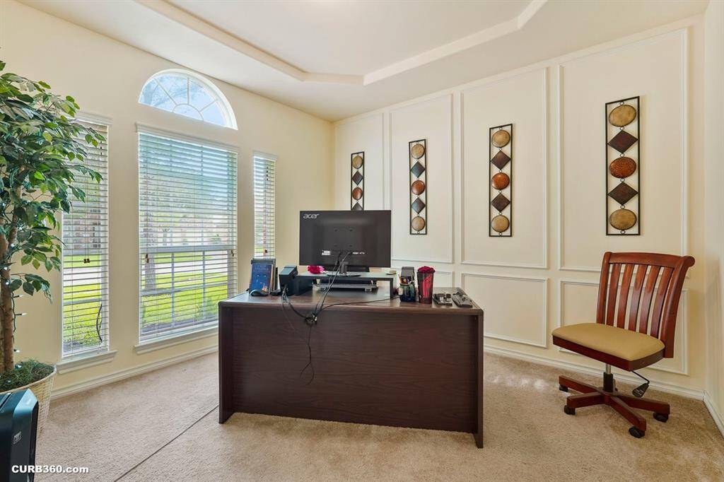 Bright home office with large windows, elegant wall paneling, and decorative accents.