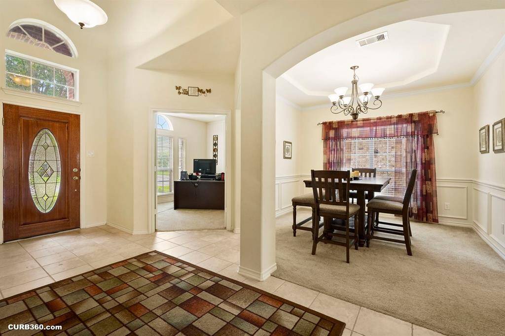 dining area with a stylish chandelier and large window. Adjacent is an office space with ample natural lighting