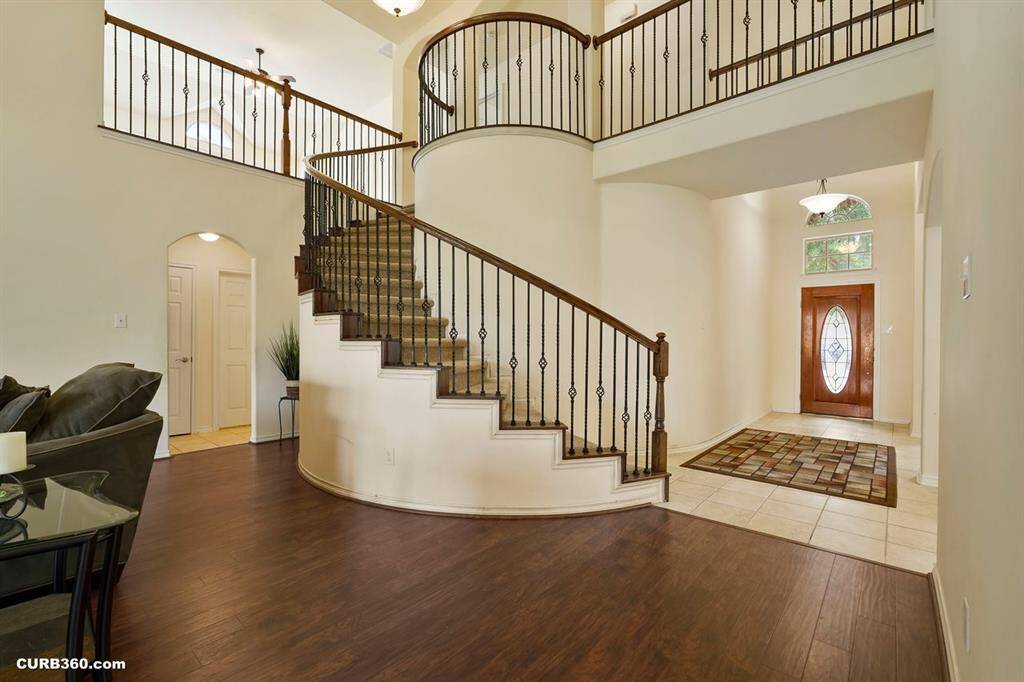 elegant entryway with a curved staircase featuring wrought iron railings.