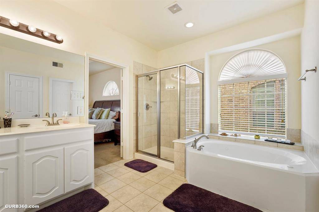Master bathroom features a glass-enclosed shower, a large soaking tub, and dual vanities