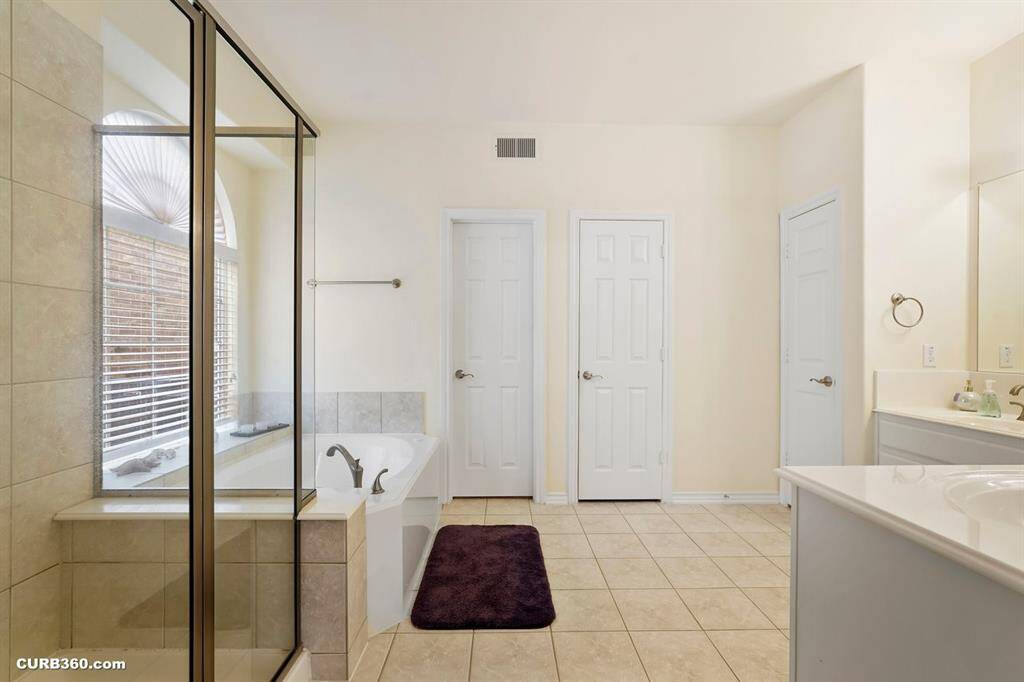 Master bathroom shower, a separate bathtub, dual sinks, and ample natural light from a large window.