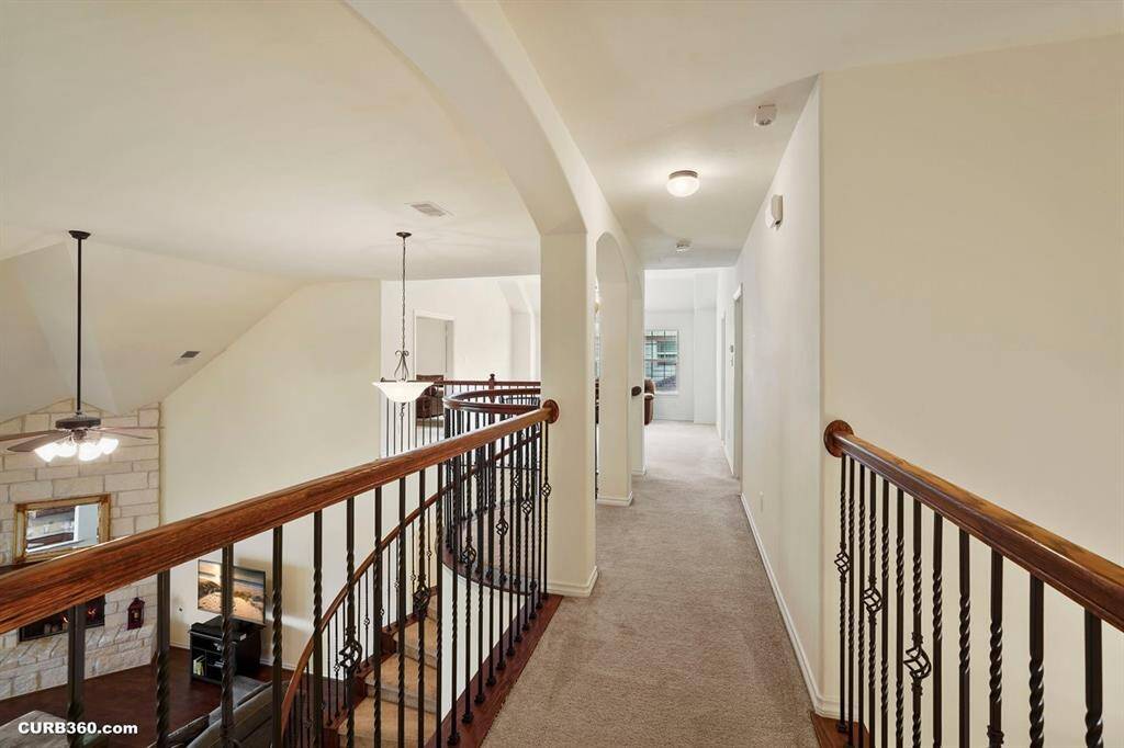upstairs hallway with arched doorways, and elegant wrought iron railings overlooking a living area