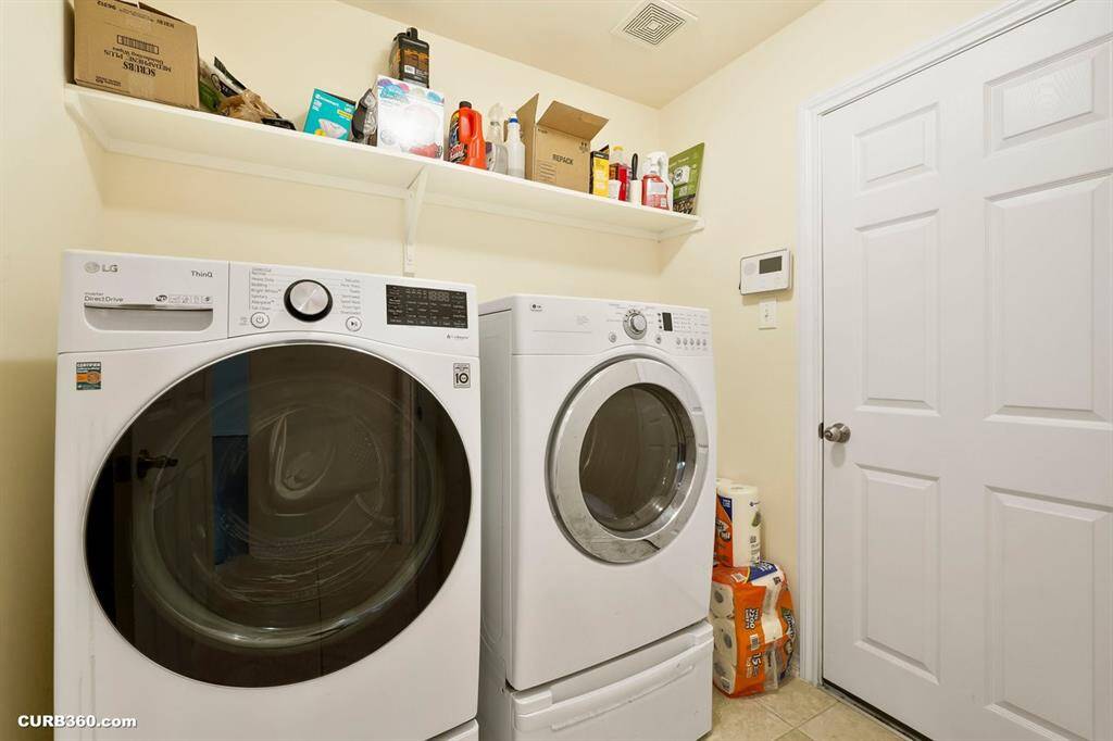 This is a well-lit laundry room featuring shelf for storage above the appliances