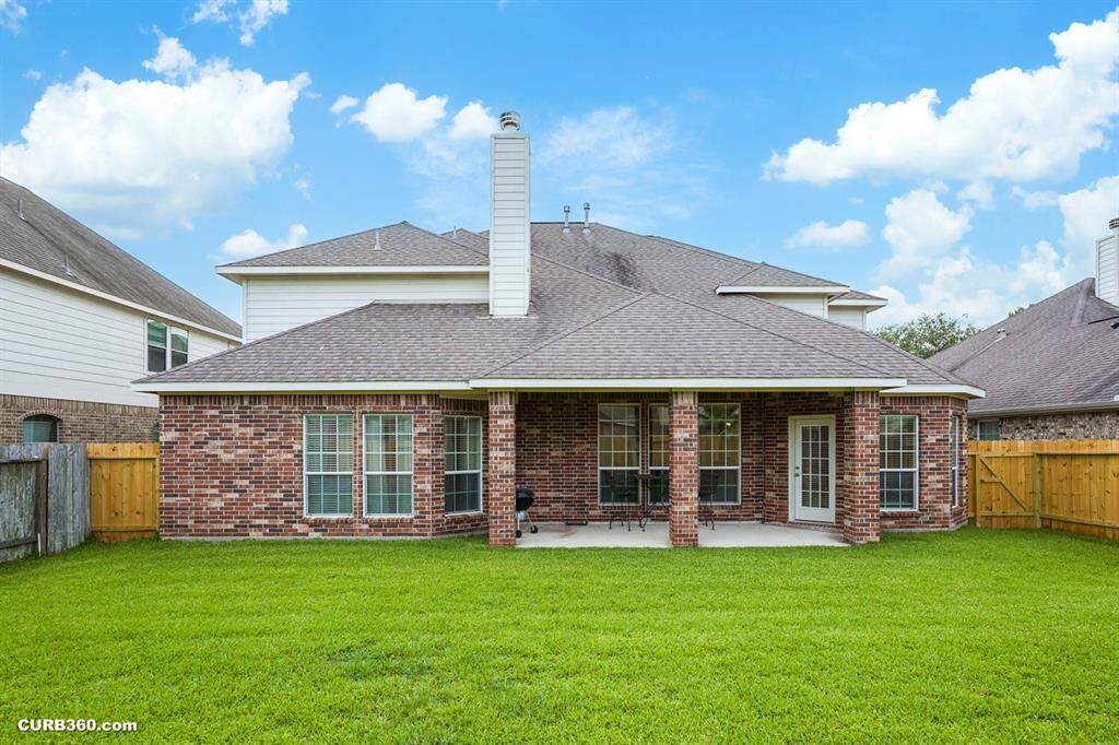 back of the home with lots of brick and covered patio