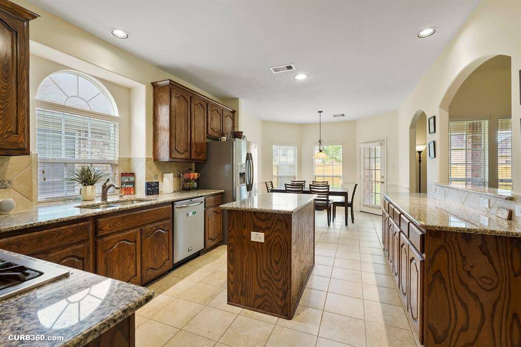 Open kitchen, wooden cabinetry, granite countertops, and a central island