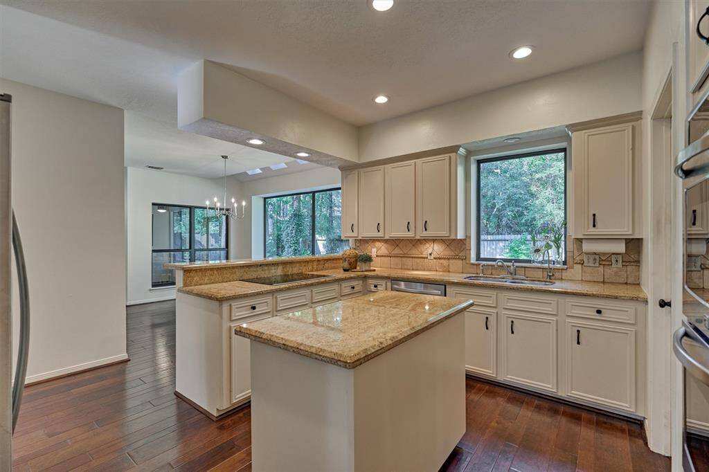 Kitchen with Induction cooktop and sink with large window overlooking backyard. Reverse osmosis water at sink. Plenty of cabinets/storage. View from study entry.