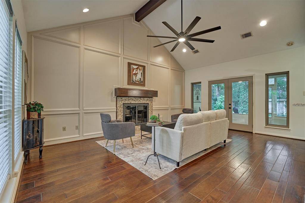 Beautiful floors, vaulted ceiling, wood-trimmed accent wall and gas log fireplace with wood beam mantle. Plenty of space for entertaining and conversation. View from entry. Double doors lead to screened back porch.