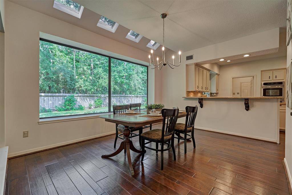 Dining Room is flooded with natural light - wall of windows and sky lights. Beautiful floors continue and is open to kitchen. Views of backyard and Screened Porch.