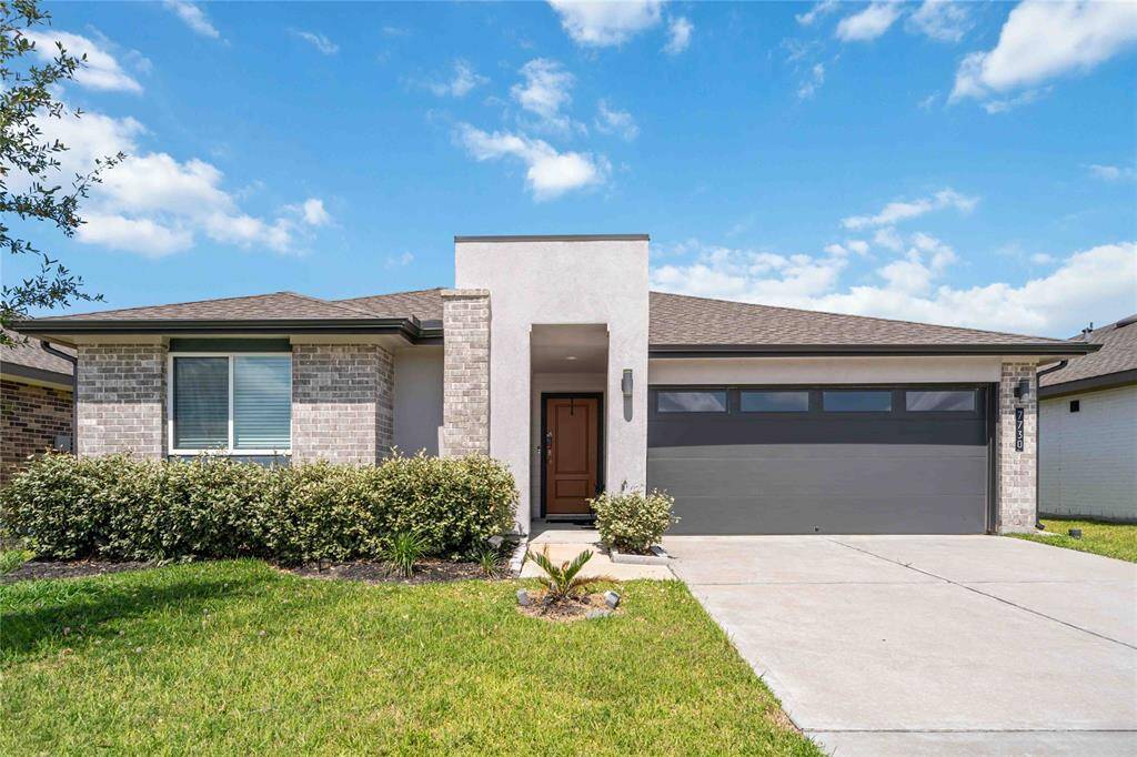 Clean exterior design with brick details, manicured lawn, and spacious driveway.