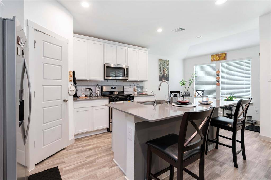 Modern kitchen with stainless steel appliances, sleek countertops, and abundant cabinetry.