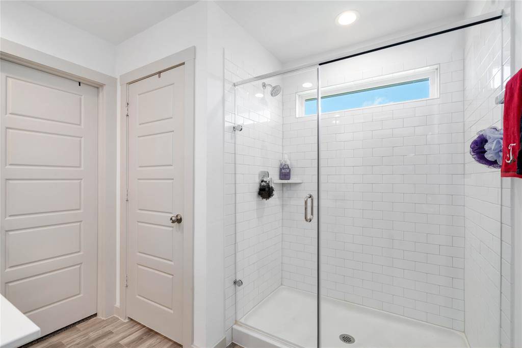 Walk-in shower with floor-to-ceiling subway tile, glass enclosure, and a large picture window for natural light.